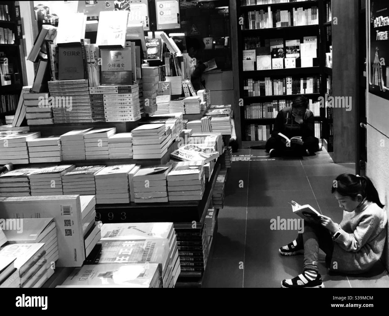 Children reading books while sitting on the floor of a local bookstore.. Stock Photo