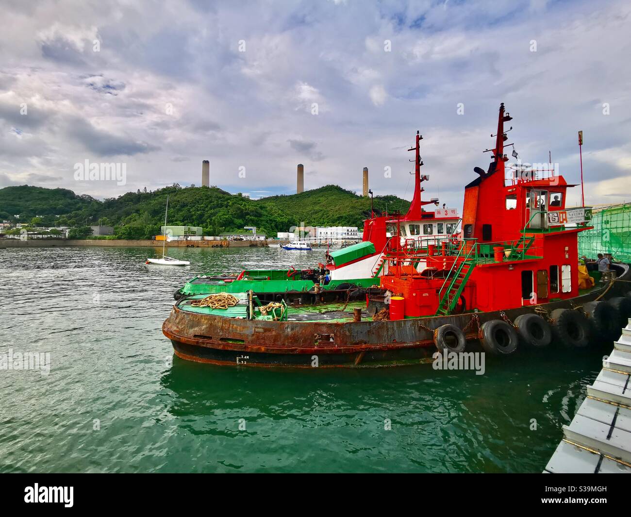 Barge boats docking at the Yung Shue Wan pier on Lamma island in Hong Kong. - Smartphone Captured Stock Image