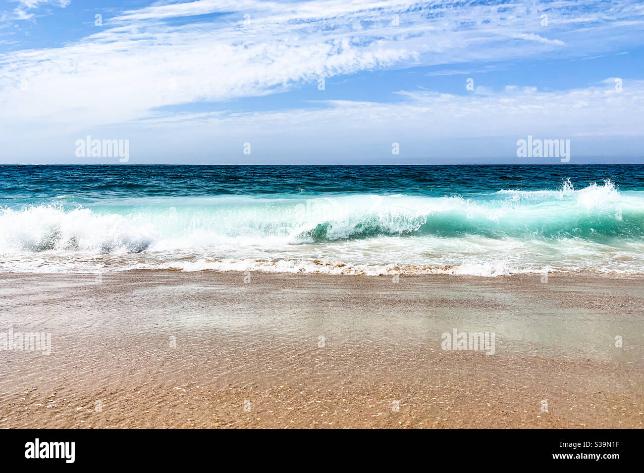 Ocean waves crushing onto sandy beach on a sunny bright day. Space for copy. - Smartphone Captured Stock Image