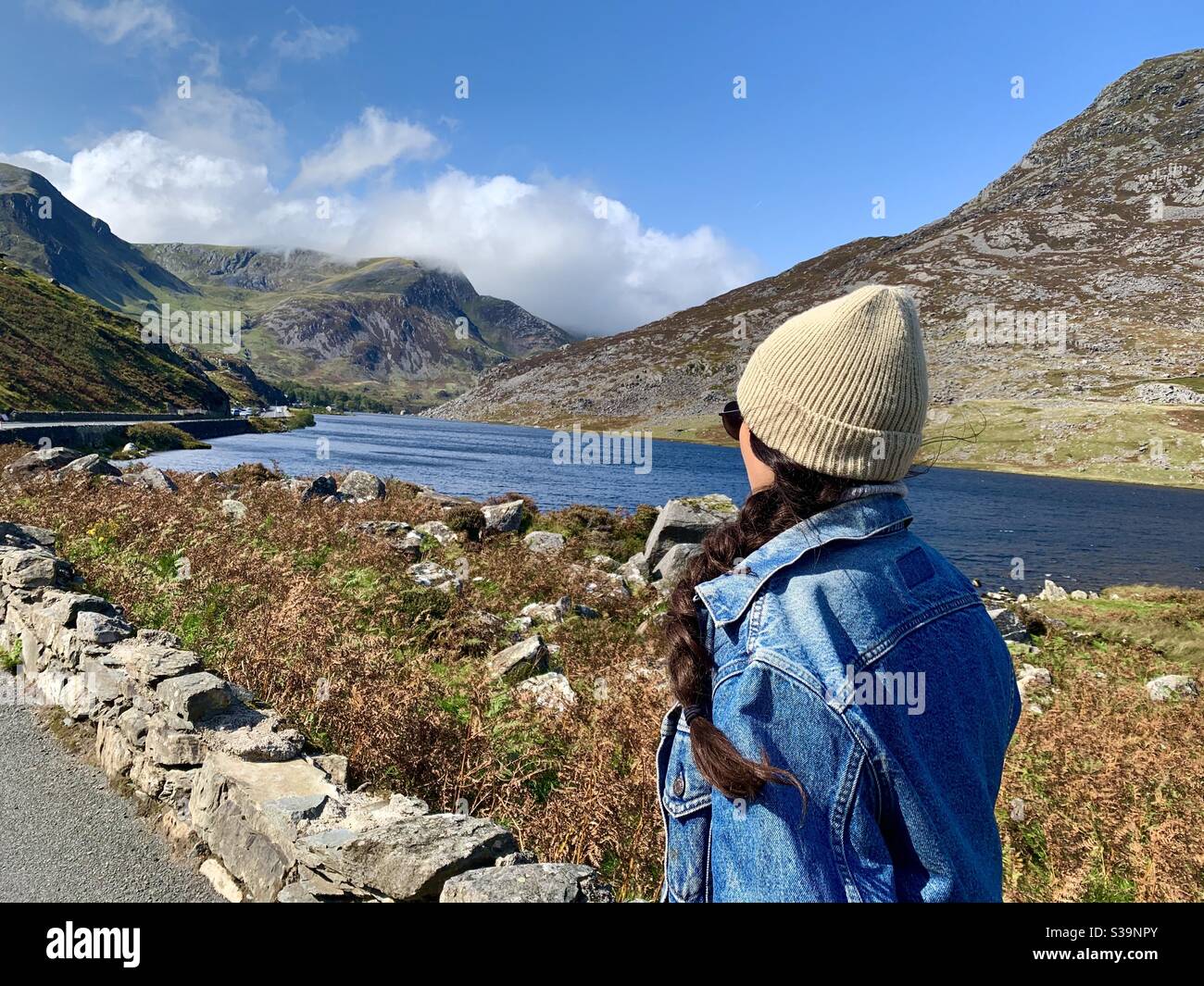 Woman looks out across the lake in Snowdonia, Wales. Stock Photo