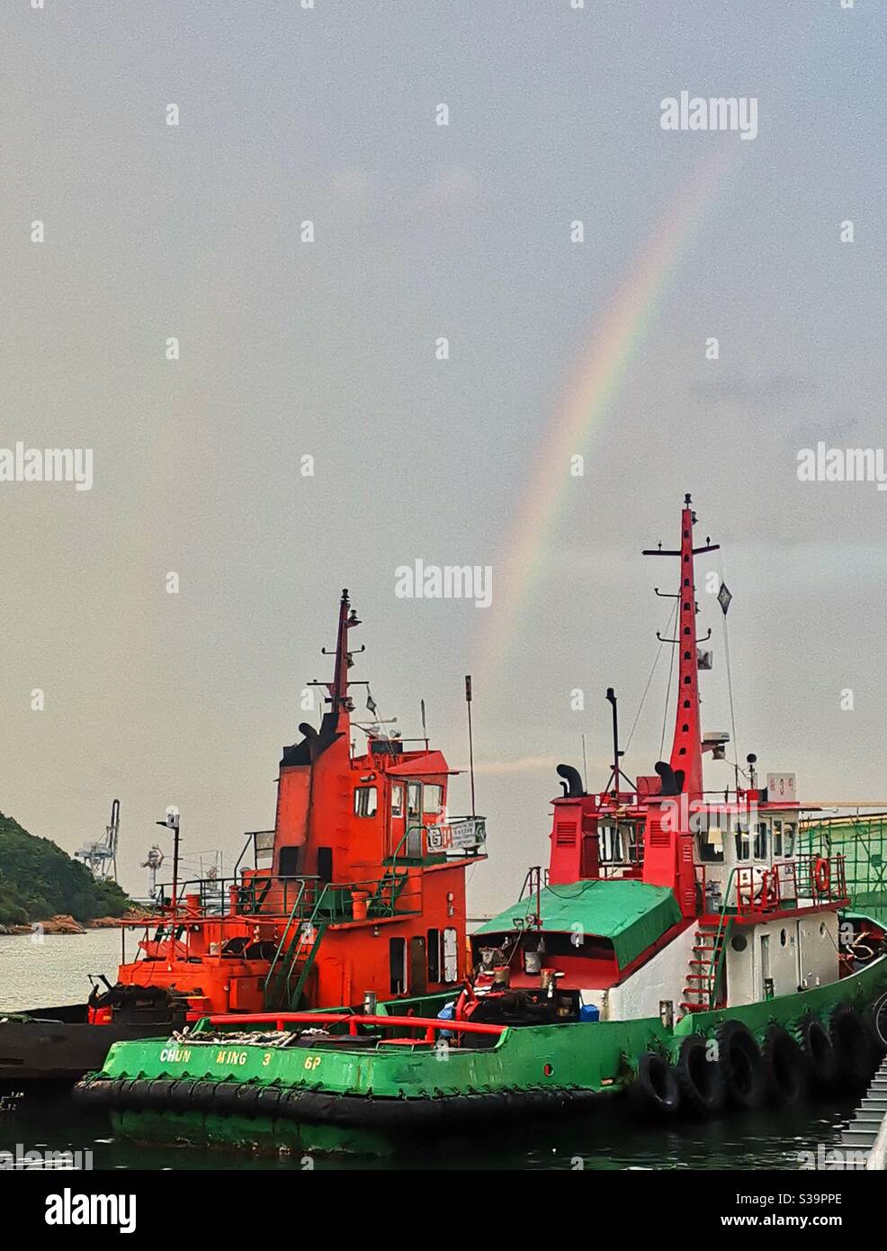 A beautiful rainbow over a barge docking at the Yung Shue Wan pier on Lamma island in Hong Kong. - Smartphone Captured Stock Image