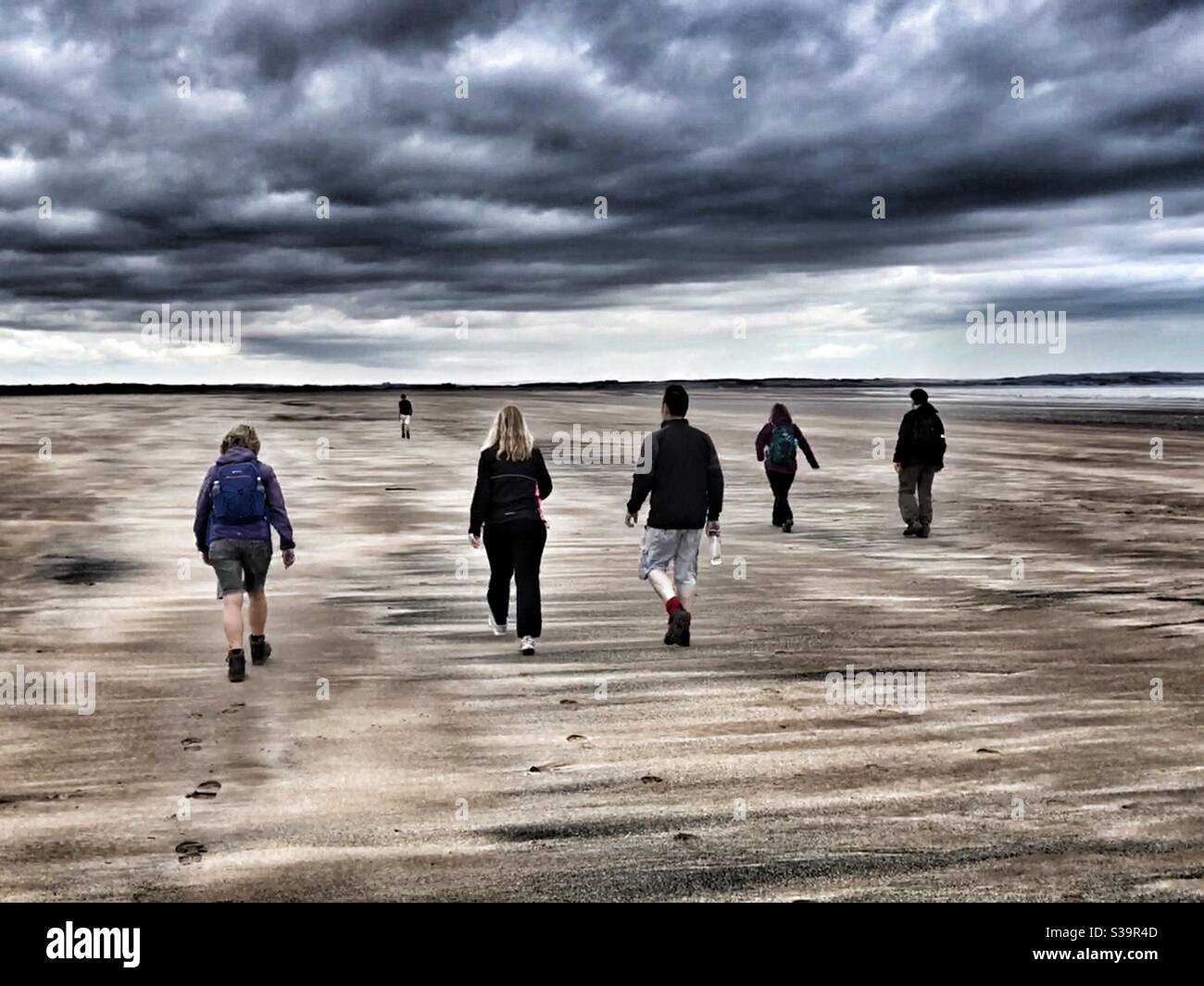 Walking on the beach under leaden sky Stock Photo