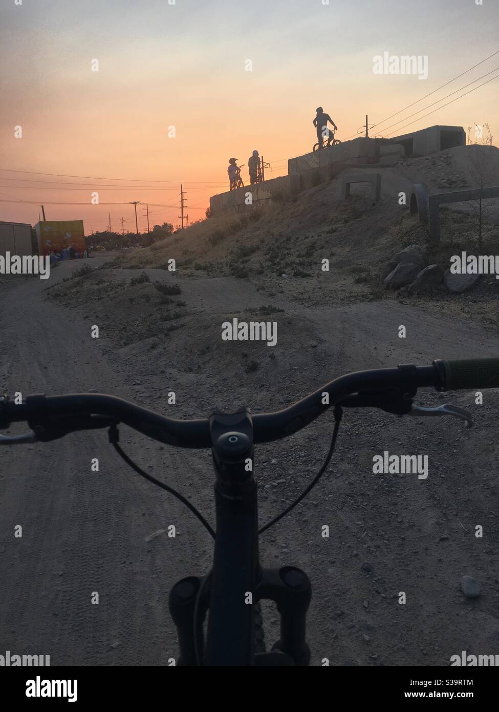 Mountain bikers at sunset shot over the handle bars. Stock Photo