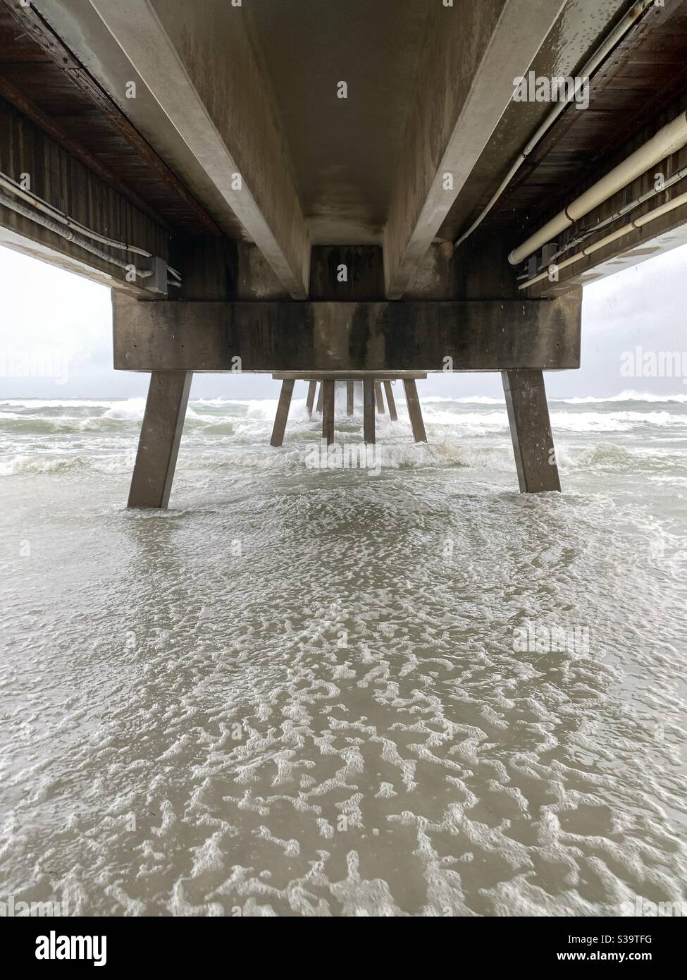 View underneath Okalossa Island fishing pier as Hurricane Sally arrives on the beach - Smartphone Captured Stock Image