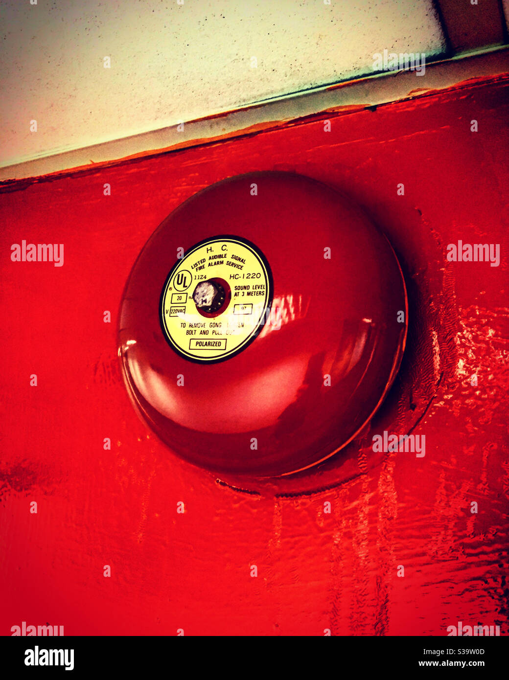 fire alarm in a corridor of a factory public building against a red wall Stock Photo