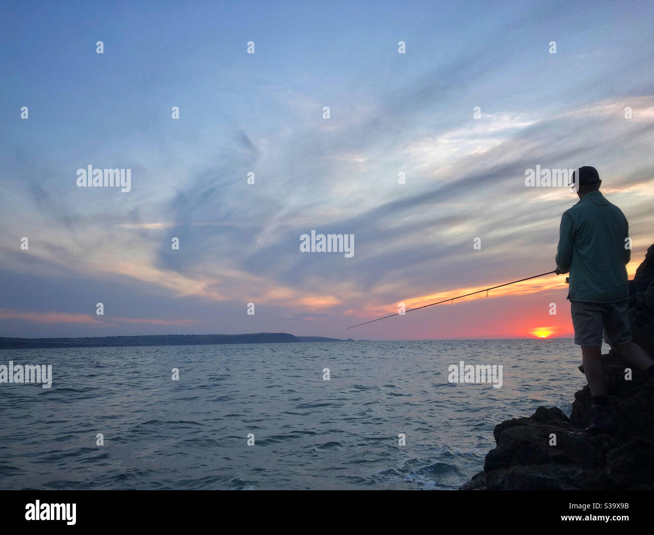 Angler fishing at sunset on the Welsh coast, September. - Smartphone Captured Stock Image