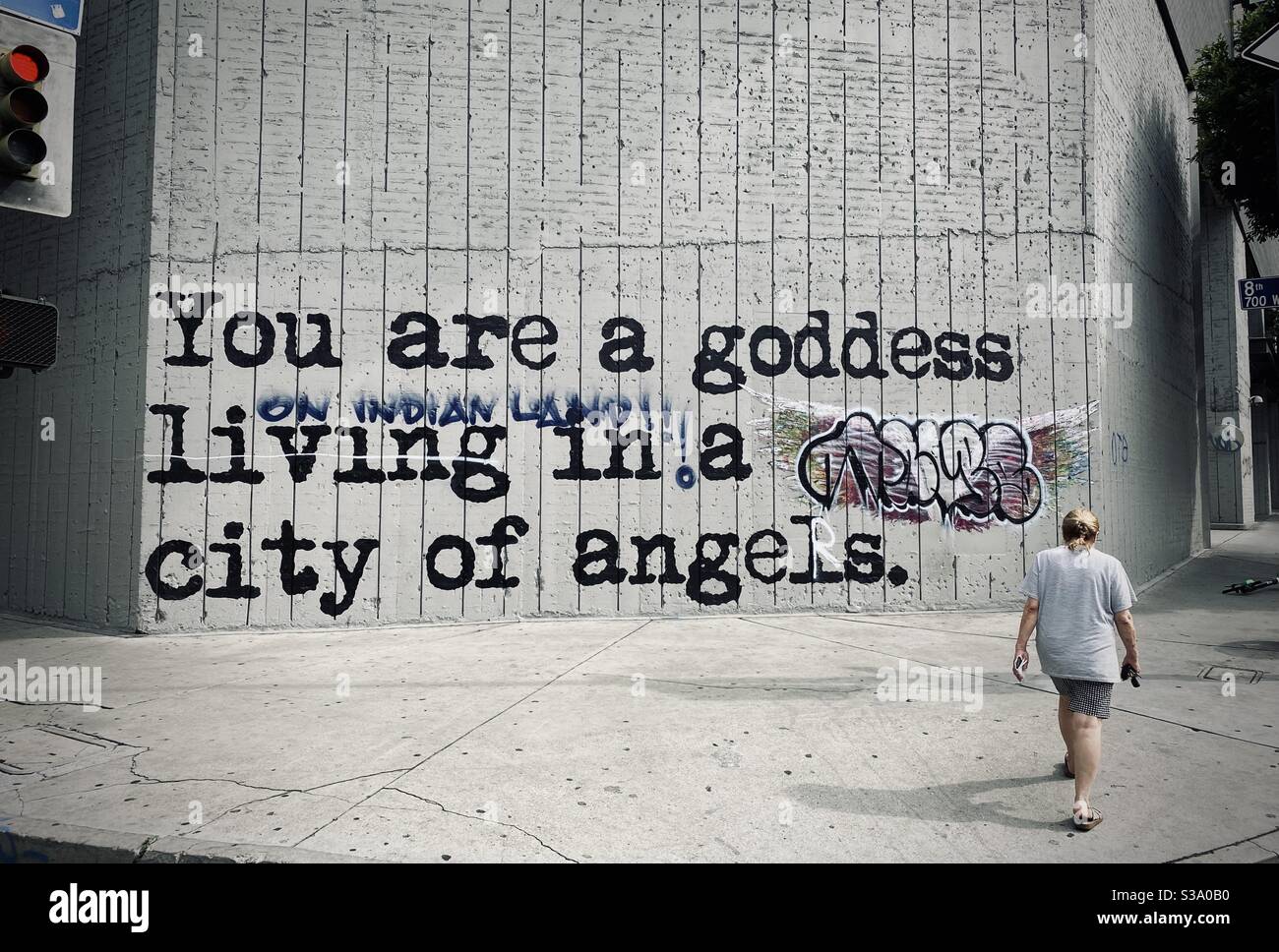 LOS ANGELES, CA, MAY 30, 2020: unidentified pedestrian walks by a mural defaced by graffiti during black lives matter protests in Downtown - Smartphone Captured Stock Image