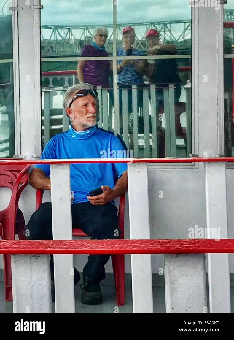 Seated man on deck of riverboat with 3 ladies in window reflection - Smartphone Captured Stock Image