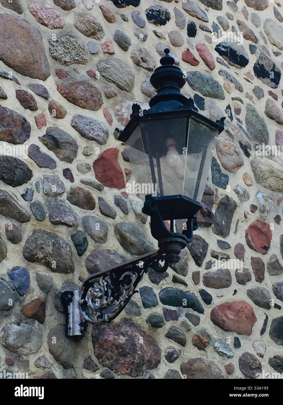 Lantern on a medieval town wall.  Cast iron.  Stone built wall Stock Photo