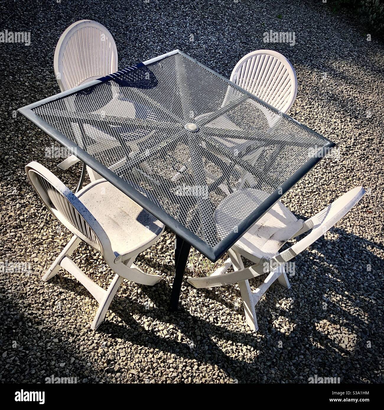 Overhead view of outdoor garden courtyard with table and plastic chairs. - Smartphone Captured Stock Image