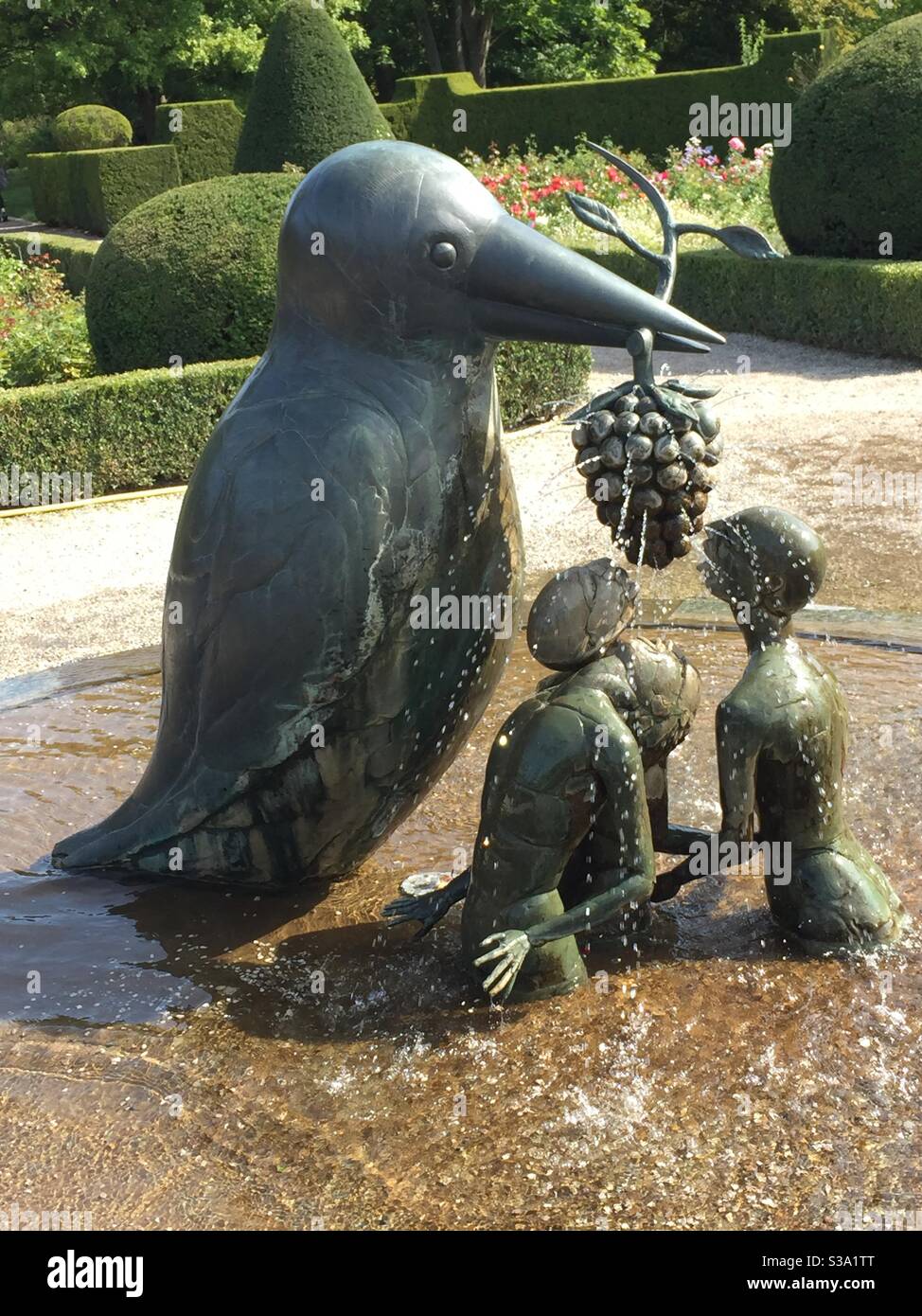 Cast metal fountain sculpture- oversized bird with grapes and 3 people. Stock Photo