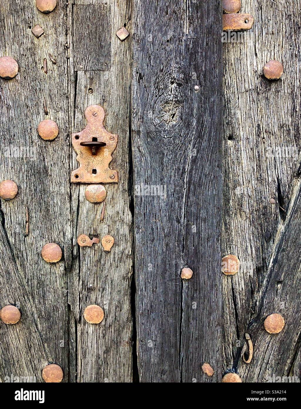 Old weathered studded oak door with rusty iron latch. - Smartphone Captured Stock Image
