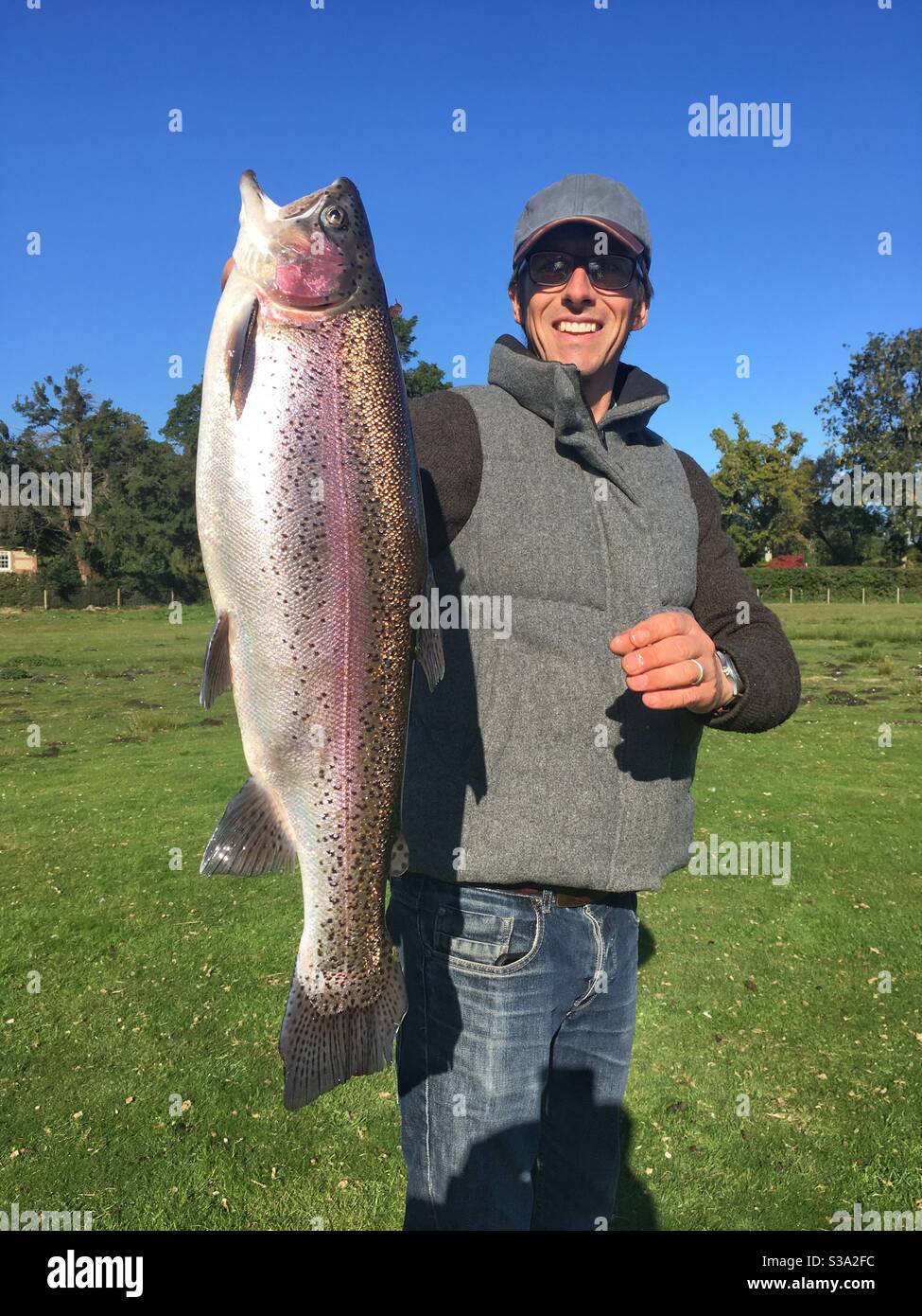 Fisherman with a large 9lb rainbow trout, Testwood trout fishery, Hampshire, England, United Kingdom. Stock Photo