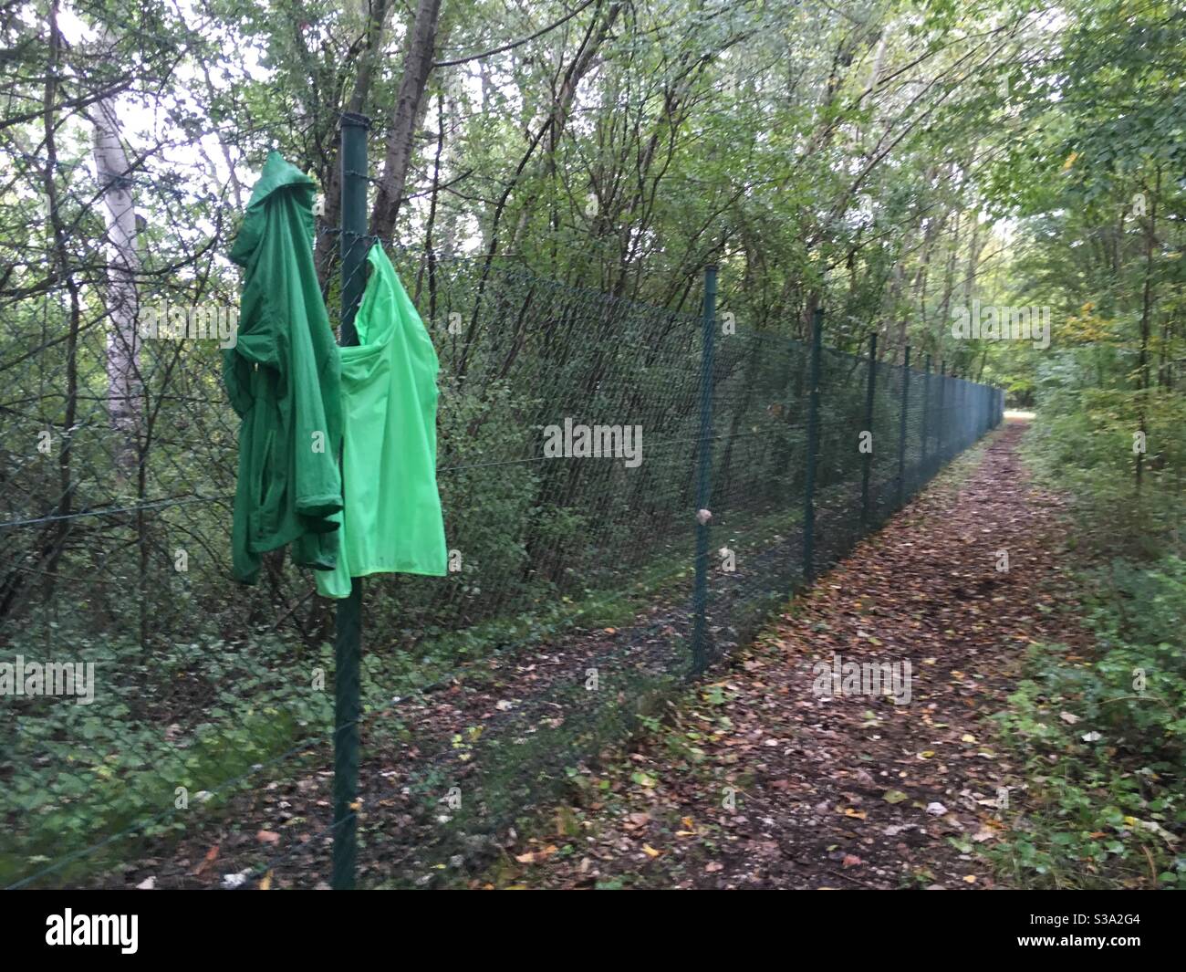 Green jackets hanging on a fence Stock Photo