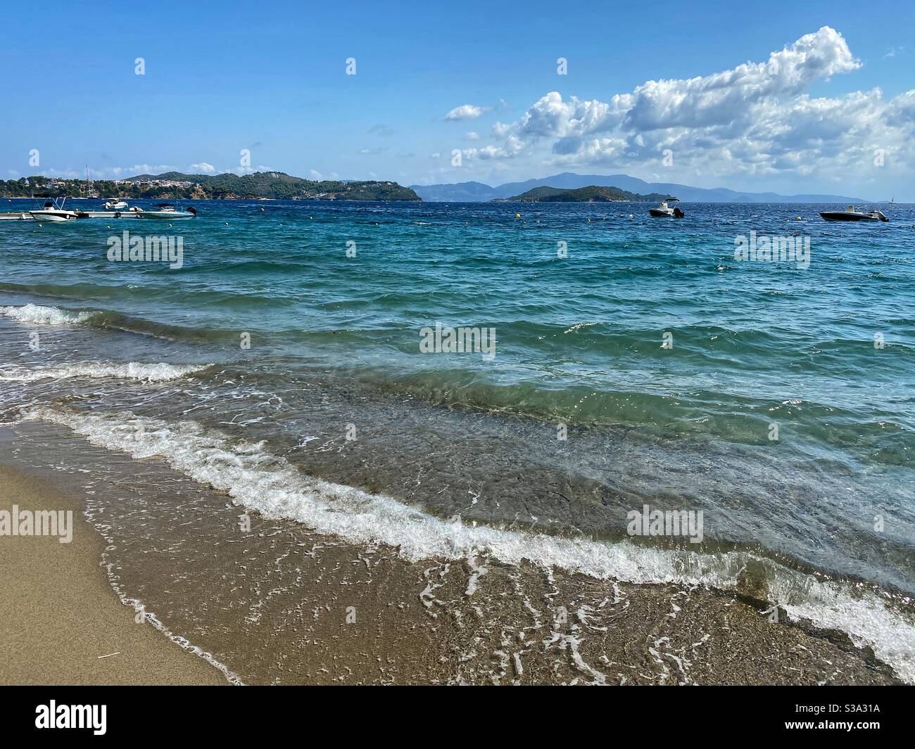 Sea view with boats and green hills at Paralia Vasilias beach on Skiathos island. - Smartphone Captured Stock Image