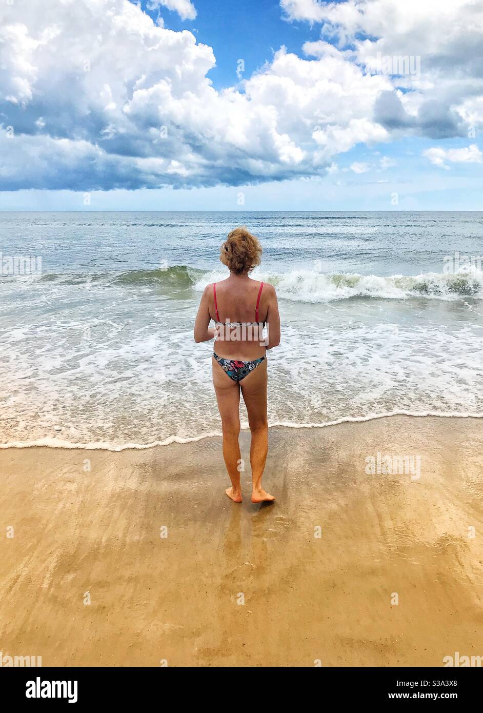 Woman in a bikini walking to the ocean’s edge, Jacksonville Beach, Florida - Smartphone Captured Stock Image