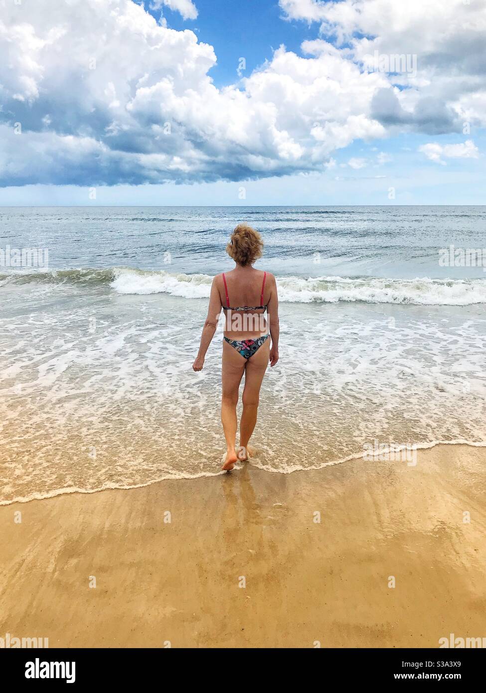 Woman in a bikini walking into the ocean, Jacksonville Beach, Florida Stock Photo