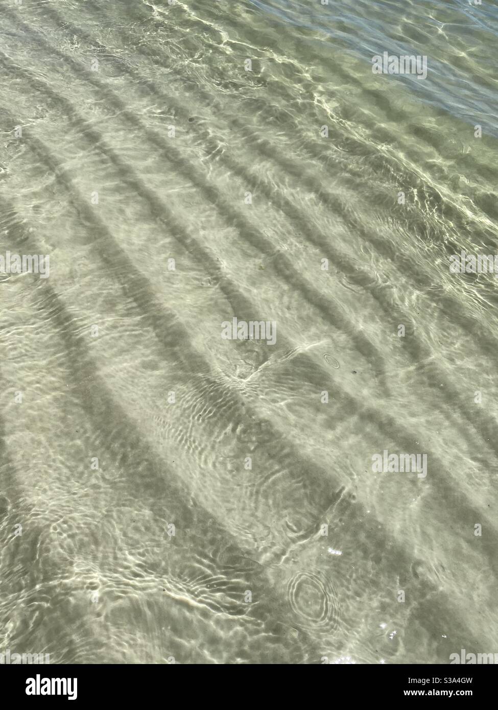 Background of sand textures and crystal clear water at the beach - Smartphone Captured Stock Image