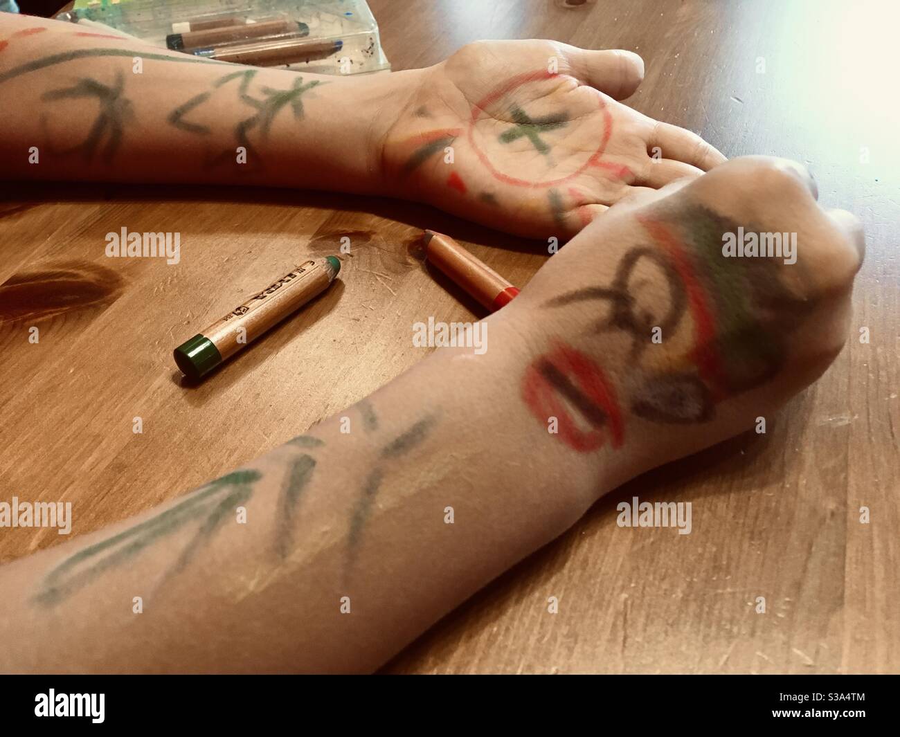 Child paiting his hands and arms with coloured body crayon Stock Photo