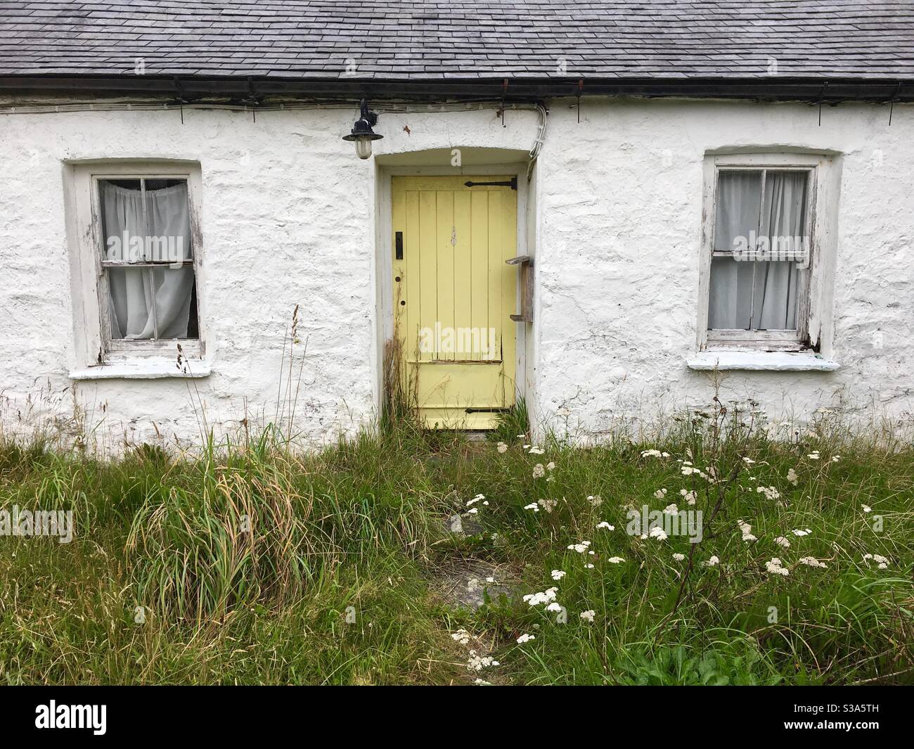 Yellow front door of ramshackle cottage - Smartphone Captured Stock Image