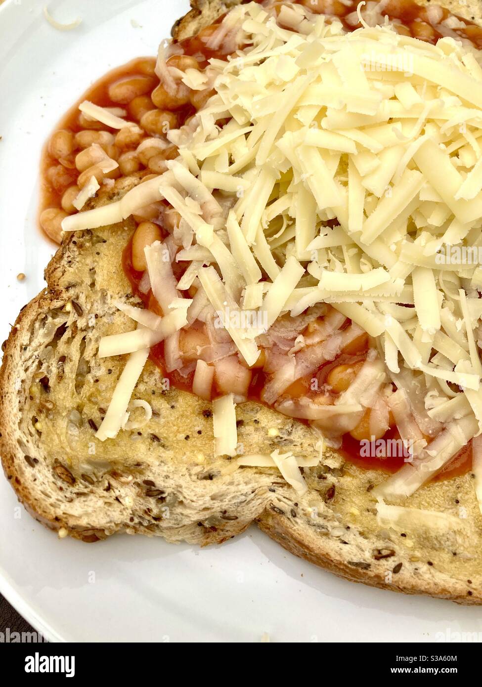 Baked beans on wholemeal seeded toast with grated cheese Stock Photo