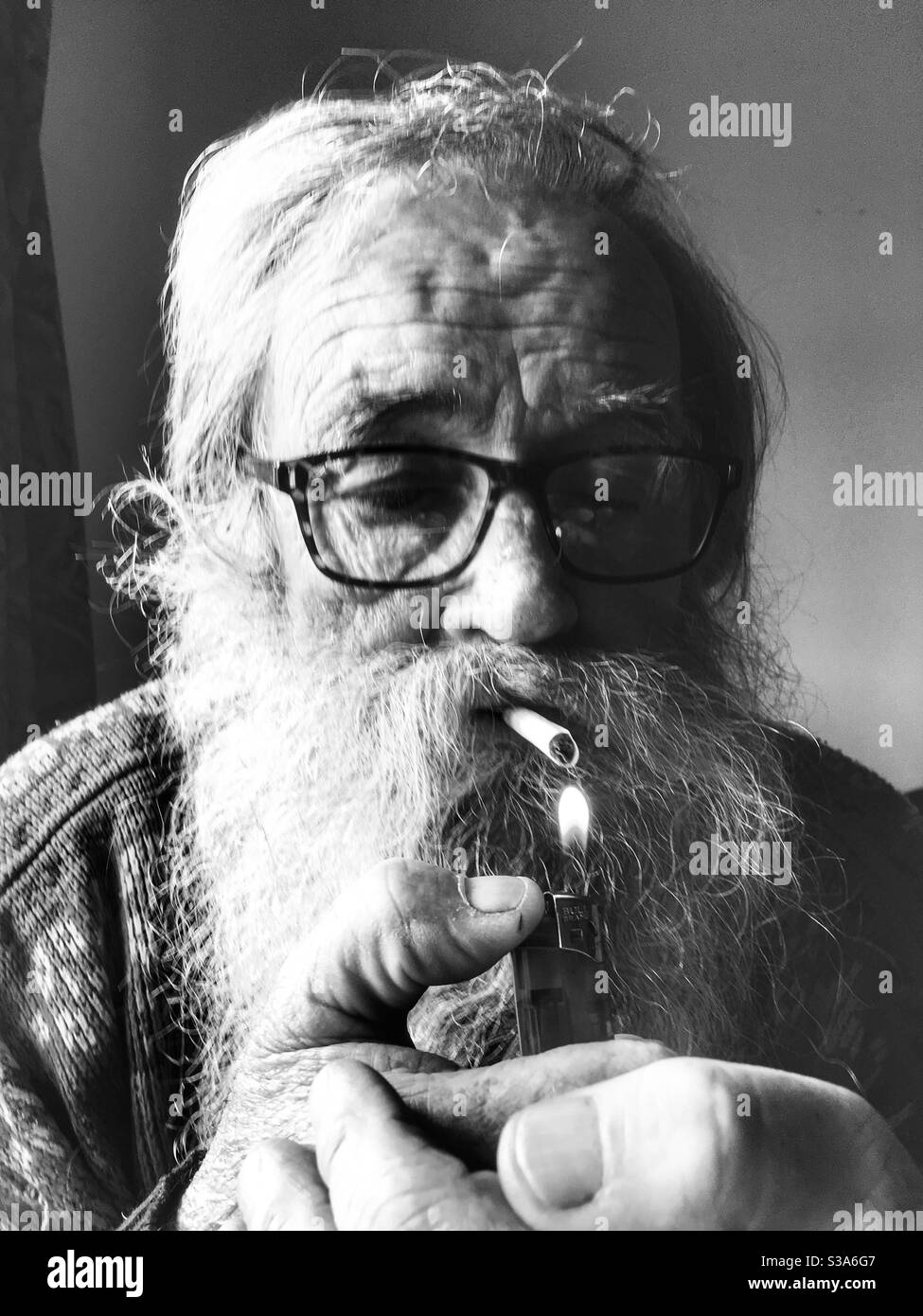 Elderly man lighting cigarette - Smartphone Captured Stock Image