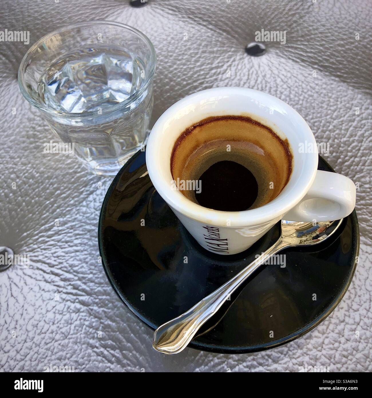 An espresso coffee and glass of water a traditional order in French