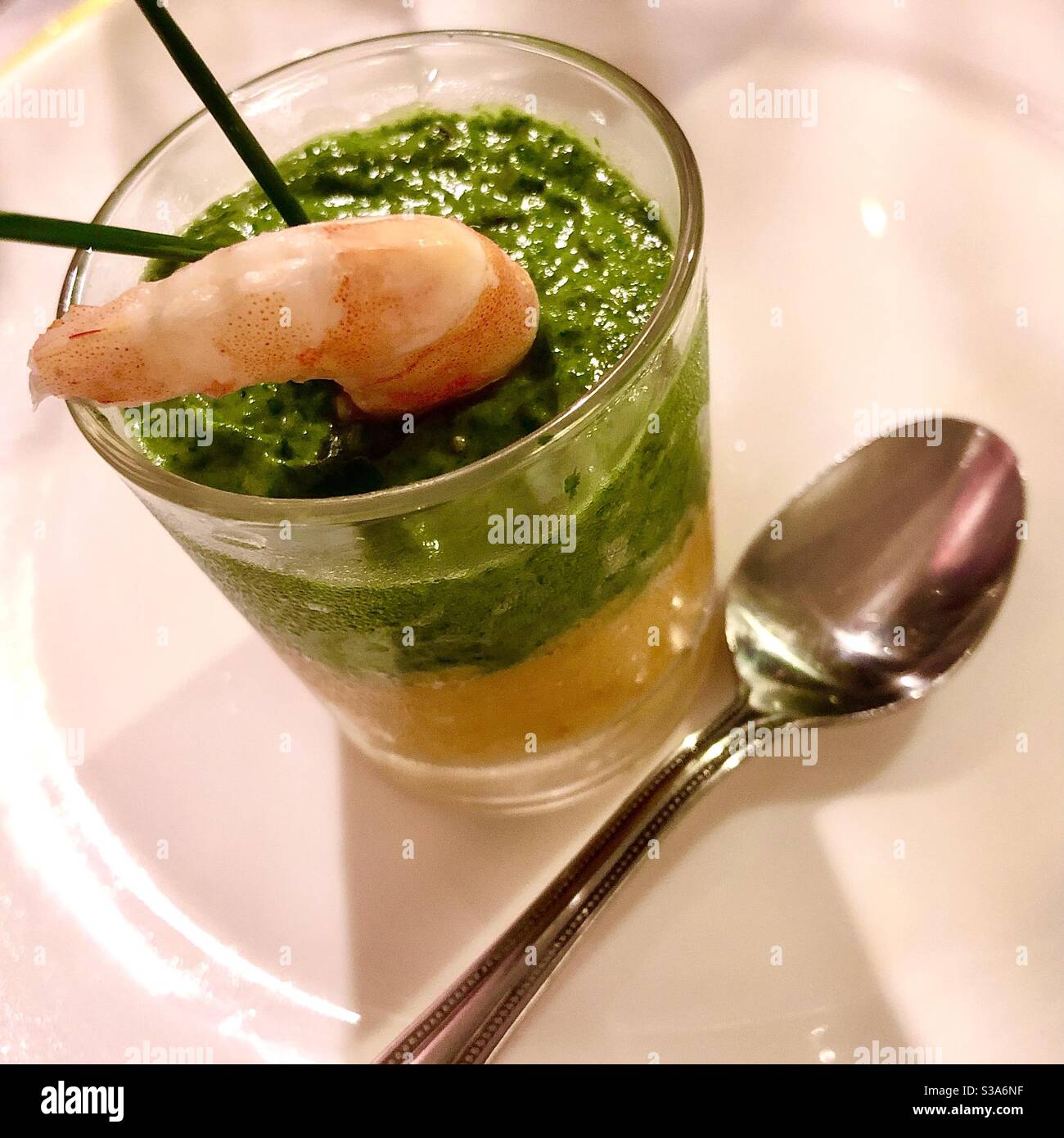 An “amuse-bouche” or “amuse-gueule” appetizer made with a shrimp and carrot purée base and spinach and avocado purée topping. Stock Photo