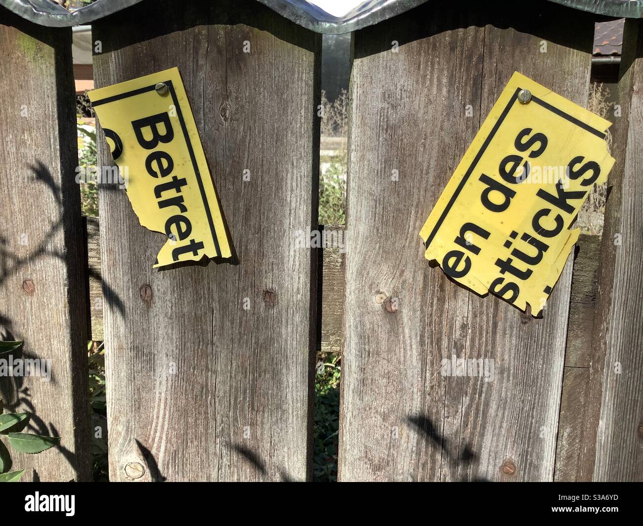 Broken German sign „Betreten des Grundstücks verboten‘“ on wooden fence