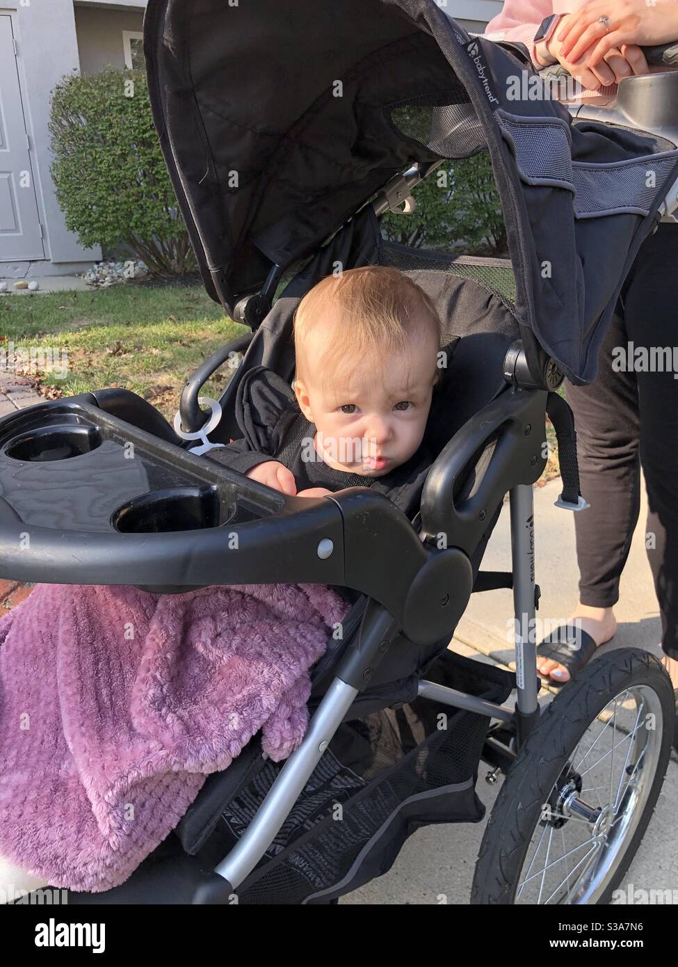 Baby makes funny face in stroller. Stock Photo