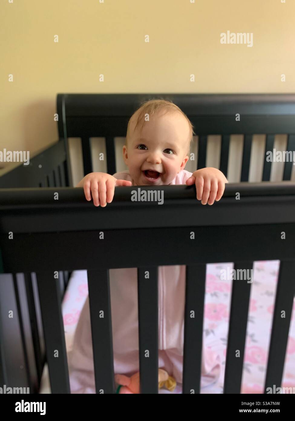 Baby laughing standing up in crib Stock Photo Alamy