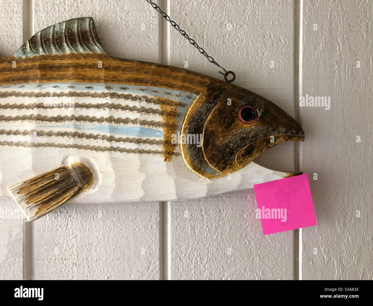 Wooden fish on an entryway wall with a blank Post-it note for a message ...