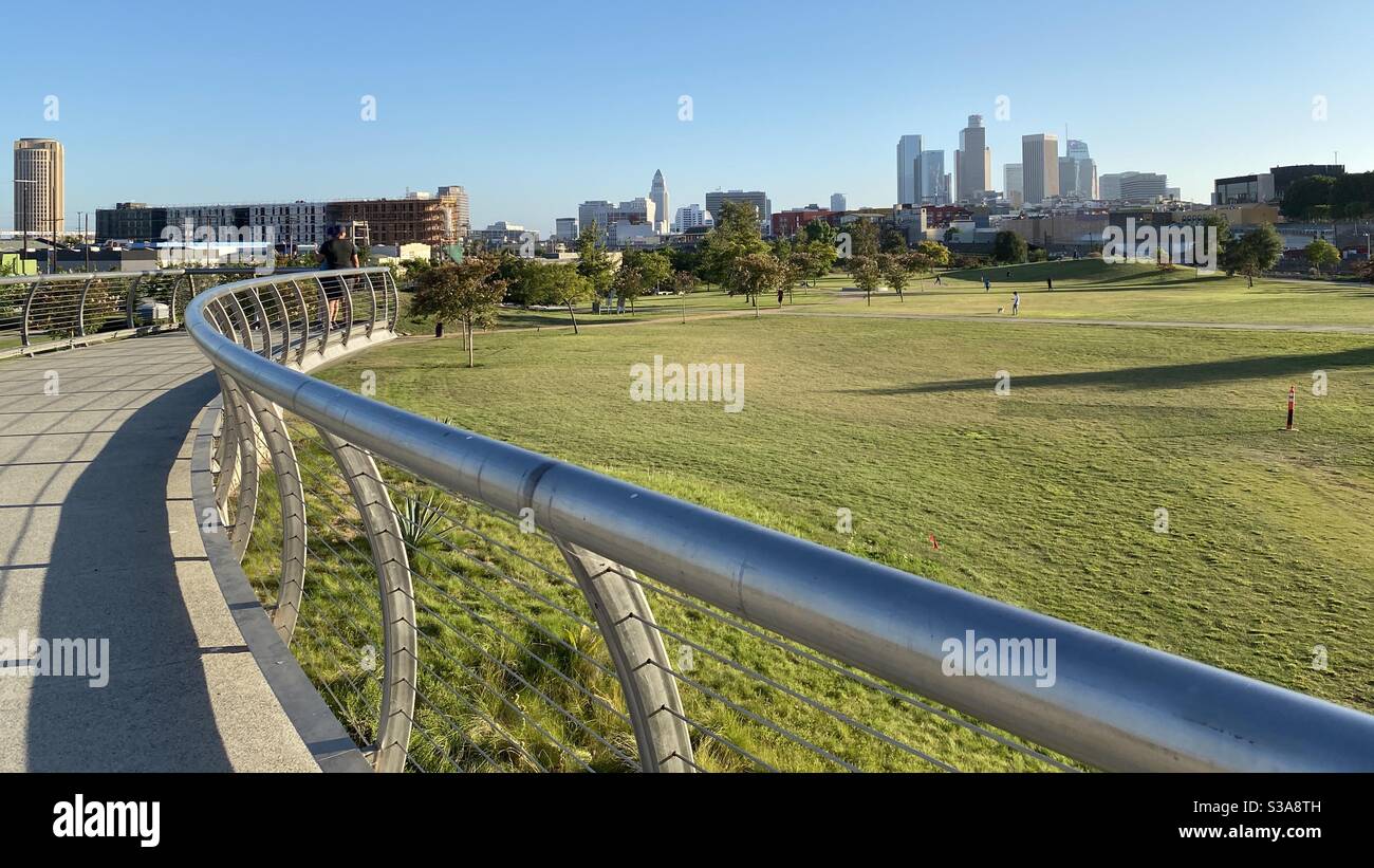 LOS ANGELES, CA, JUL 2020: curving metal handrail on walkway overlooking Los Angeles State Historic Park, with Downtown skyline in the distance - Smartphone Captured Stock Image