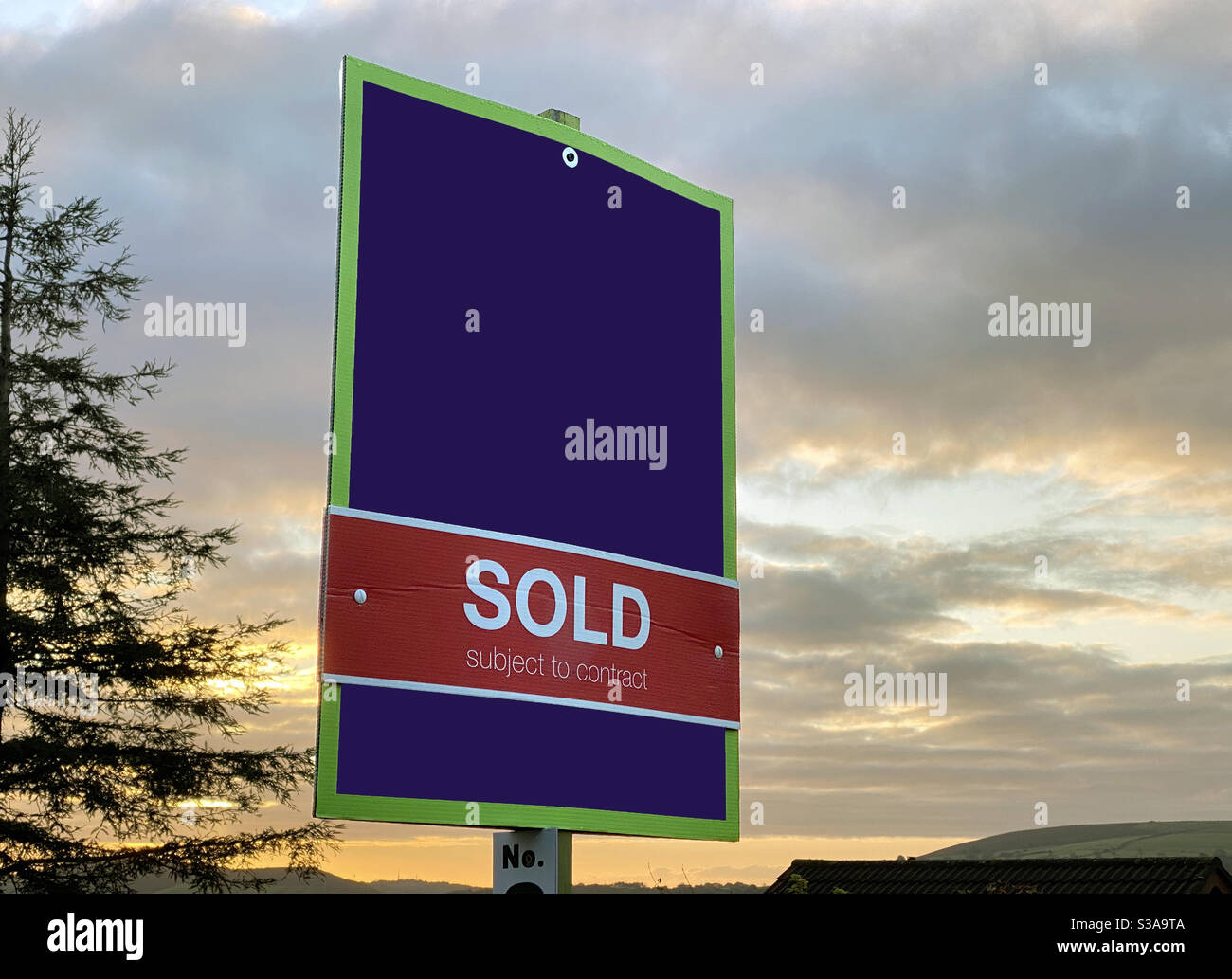 “Sold” sign against a dawn sky. No people. Copy space. Stock Photo