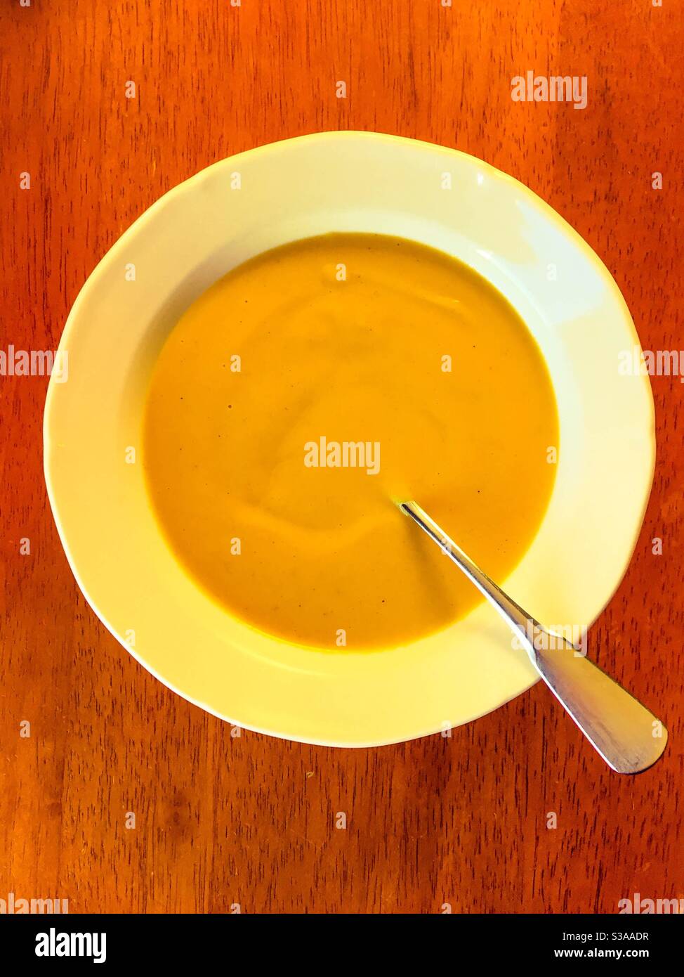 Squash soup in white bowl with spoon. Stock Photo