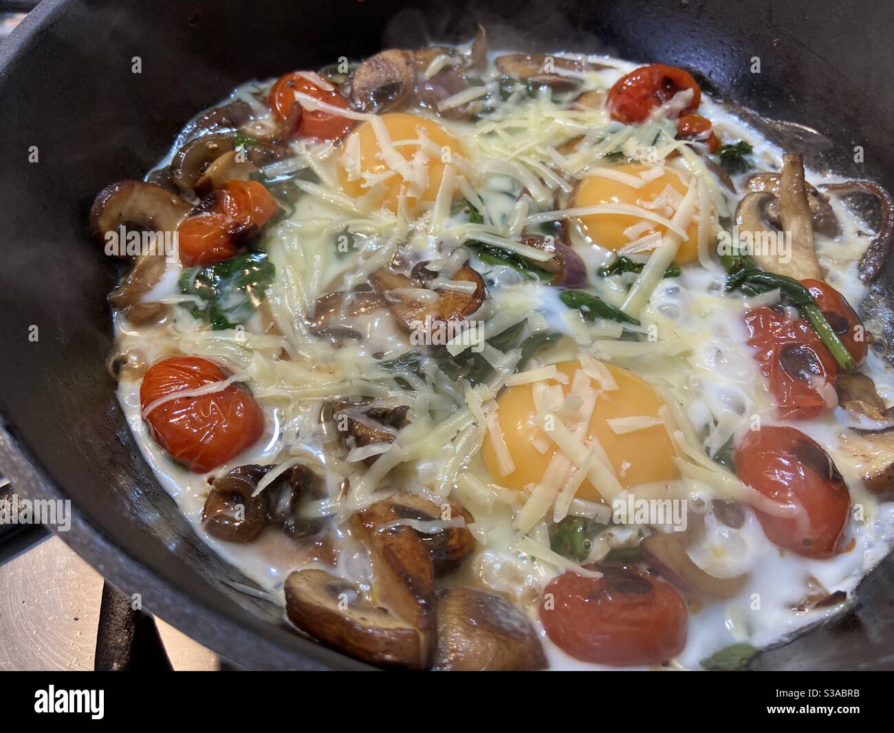 Three Egg Italian Breakfast with tomatoes spinach and Parmesan Stock Photo