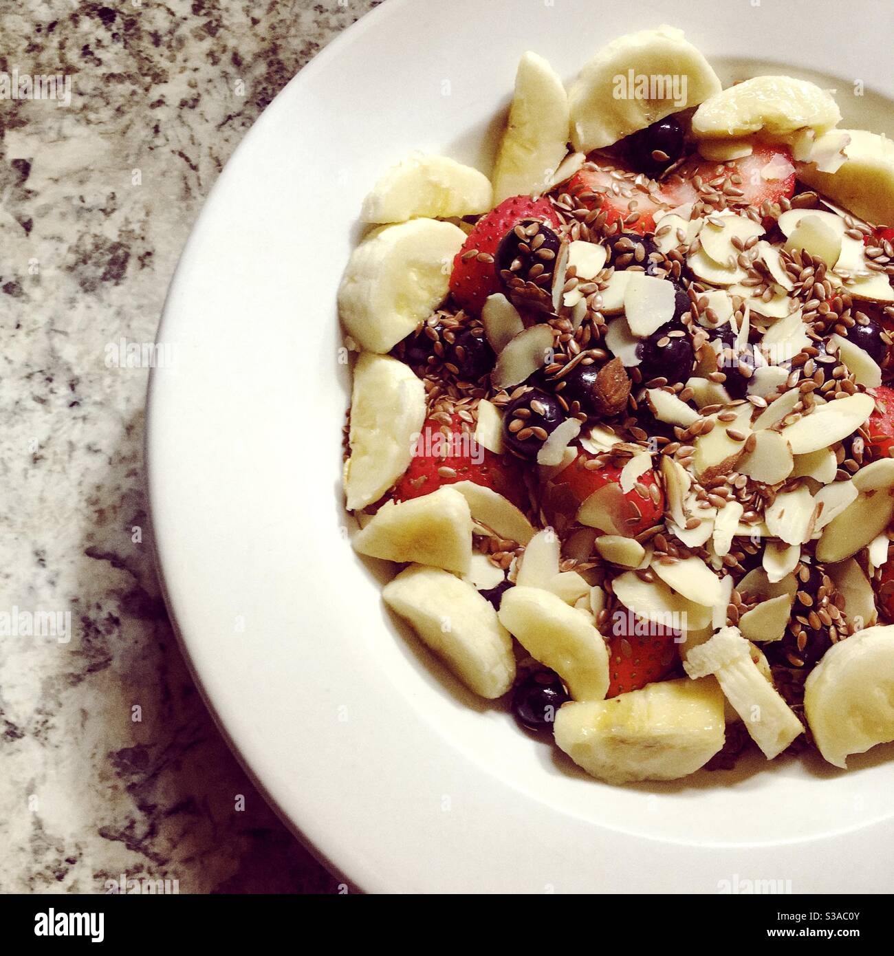 Breakfast cereal with banana, raw oats, blueberries, strawberries, slivered almonds, and