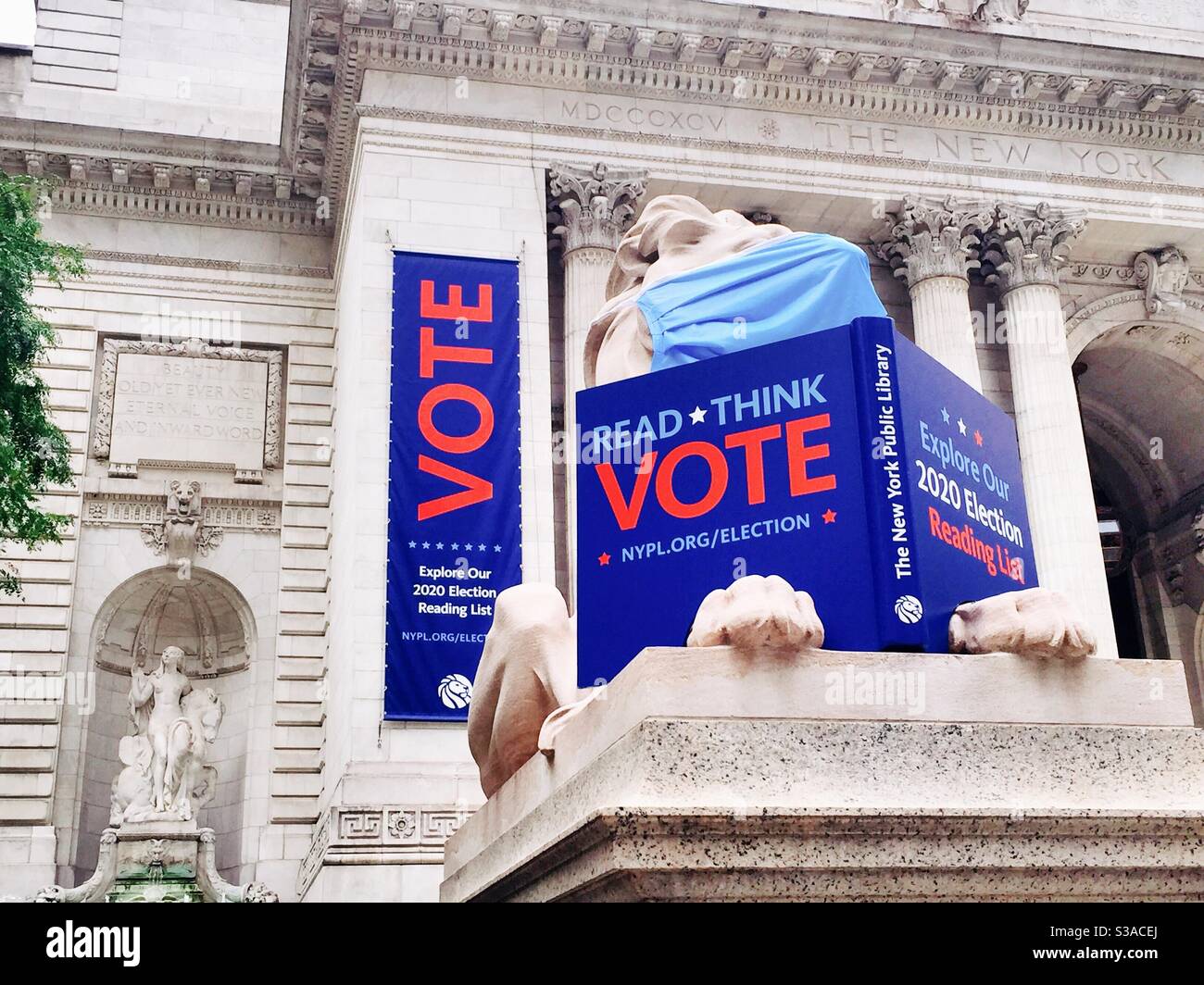 The new York public library lion reminds New Yorkers to vote with a sign and a banner while wearing a protective face mask to encourage protection against COVID-19, NYC, USA - Smartphone Captured Stock Image