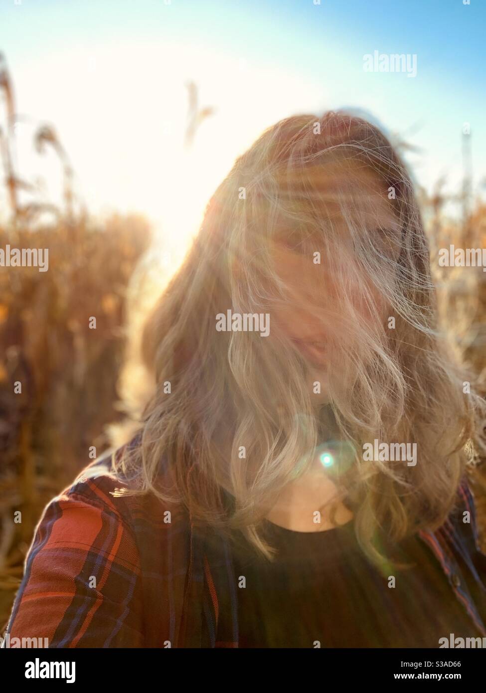 Woman with blonde hair blowing in the wind with sun flare - Smartphone Captured Stock Image