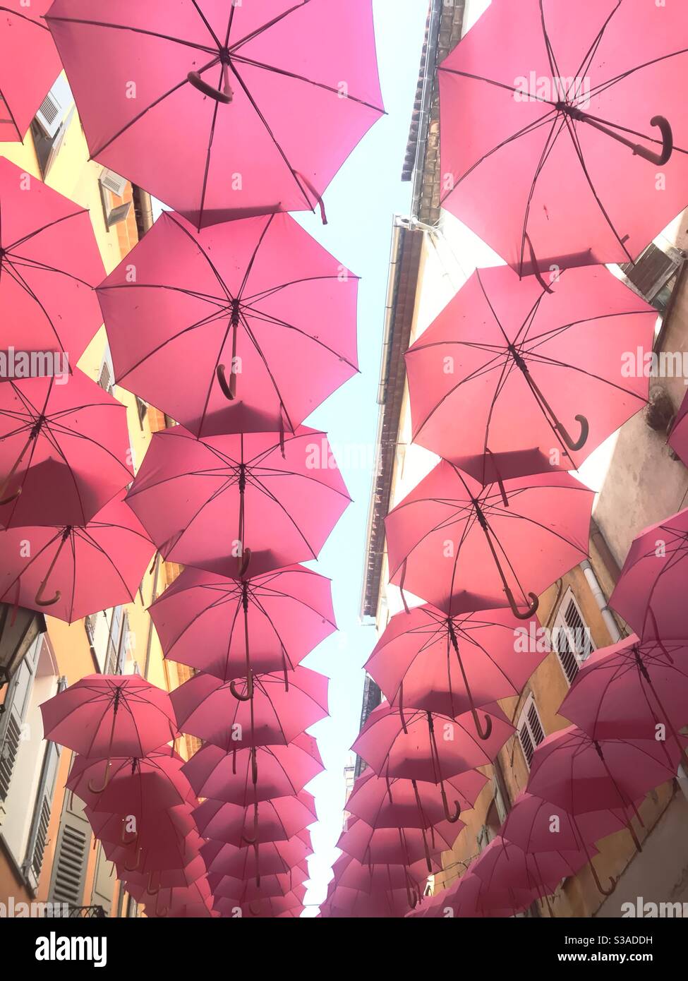 Pink umbrellas on display in the centre of Grasse, France - Smartphone Captured Stock Image