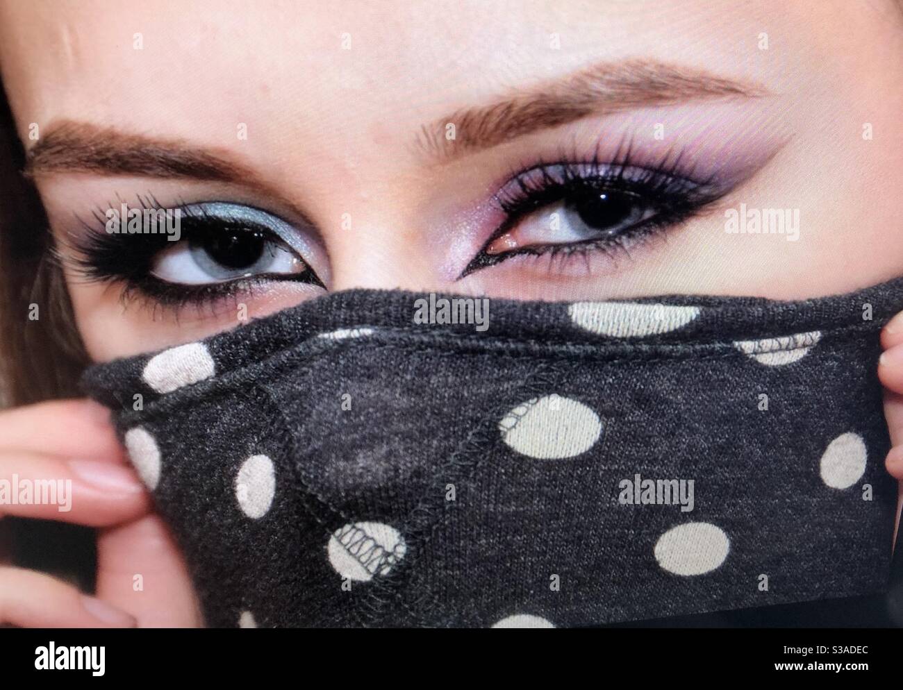 Beautiful young woman, cotton facemask. Pretty blue eyes Stock Photo