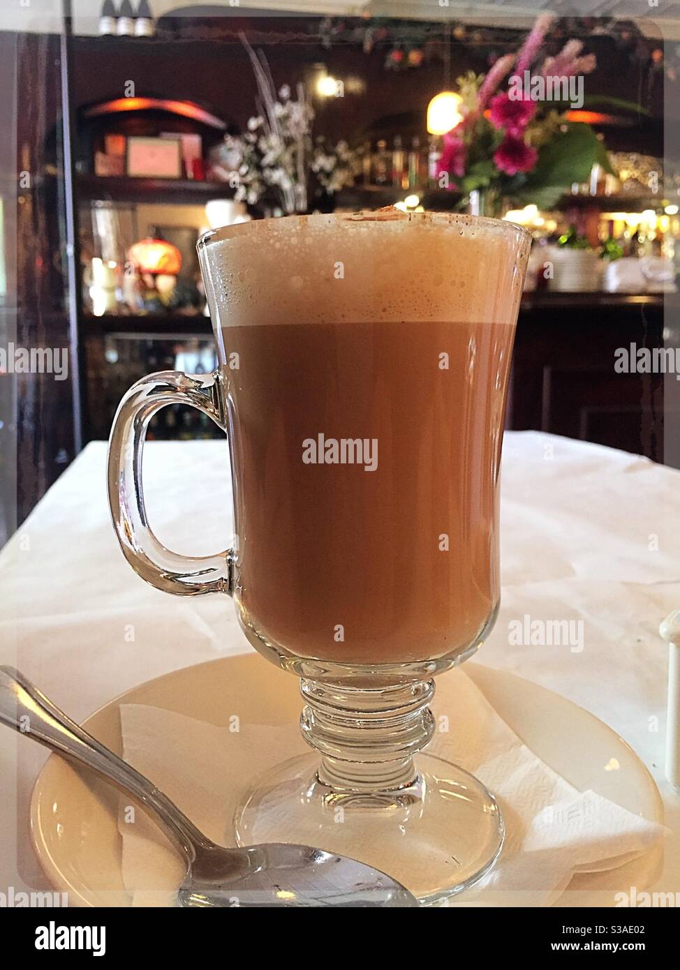 Cappuccino served in a clear glass mug at an upscale French bistro in Soho, NYC, USA - Smartphone Captured Stock Image
