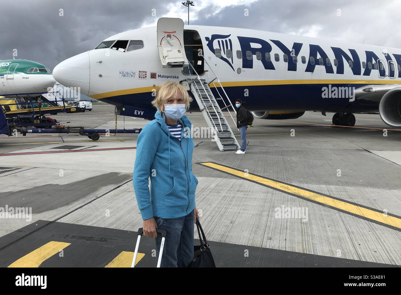 Travel in covid 19 restrictions, masked passenger waiting to board a Ryanair plane at Dublin airport with Aer Lingus plane in background - Smartphone Captured Stock Image