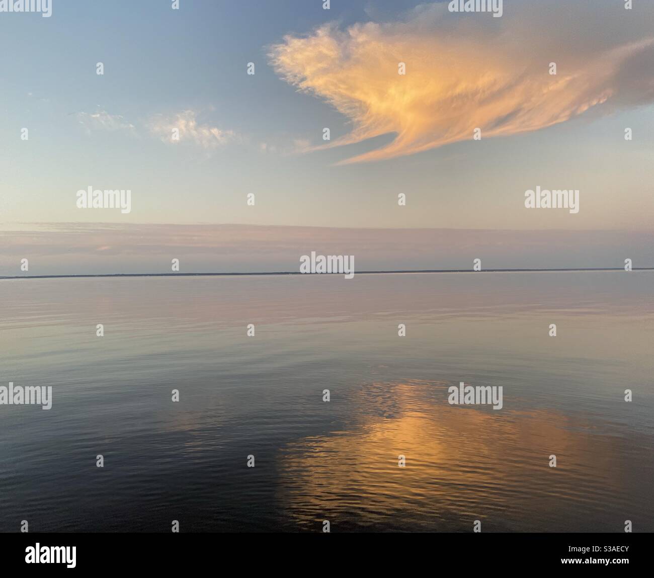 Large colorful sunset cloud reflecting onto still bay water Stock Photo ...
