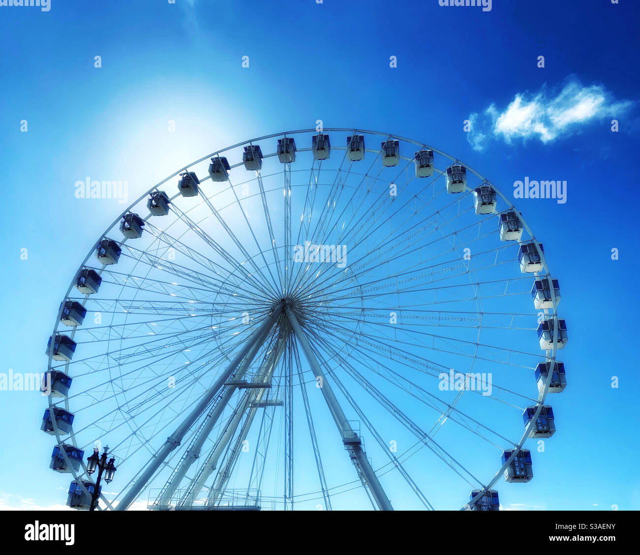 A Ferris wheel somewhere in Europe. The sun is shining - it’s summer and time to enjoy the fun fair! Photo Credit - ©️ COLIN HOSKINS. - Smartphone Captured Stock Image