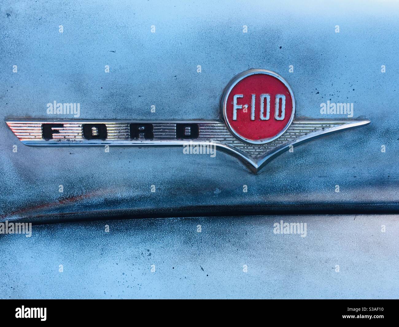 Ford F100 flatbed truck badge -silver and red on blue background Stock Photo