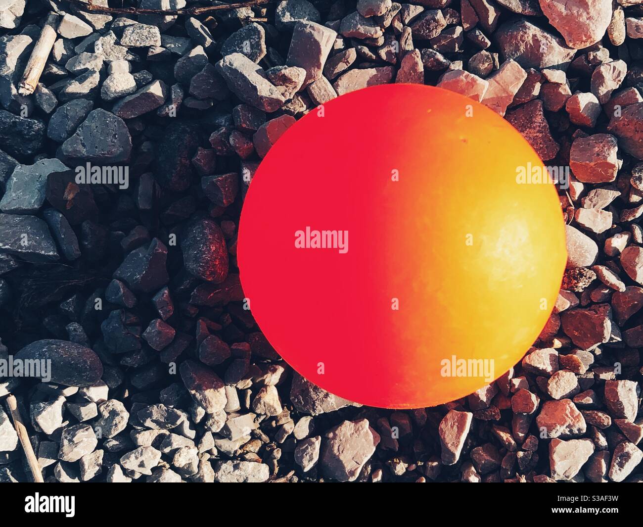 Orange plastic ball on gravel stone Stock Photo