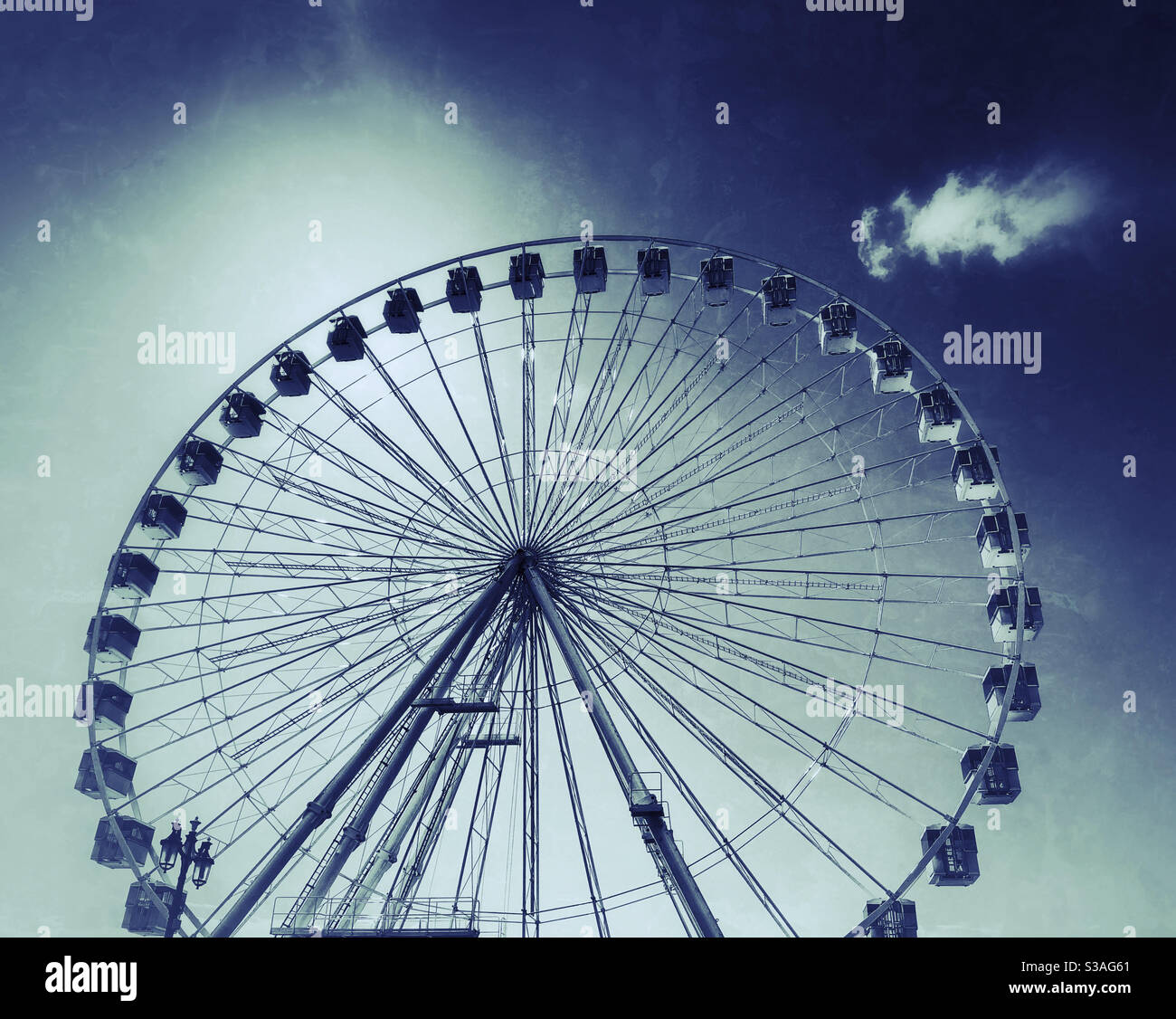 A lone cloud overlooks an imposing Ferris Wheel somewhere in the UK. A great tourist attraction - with interesting views from the top! Photo Credit - ©️ COLIN HOSKINS. - Smartphone Captured Stock Image