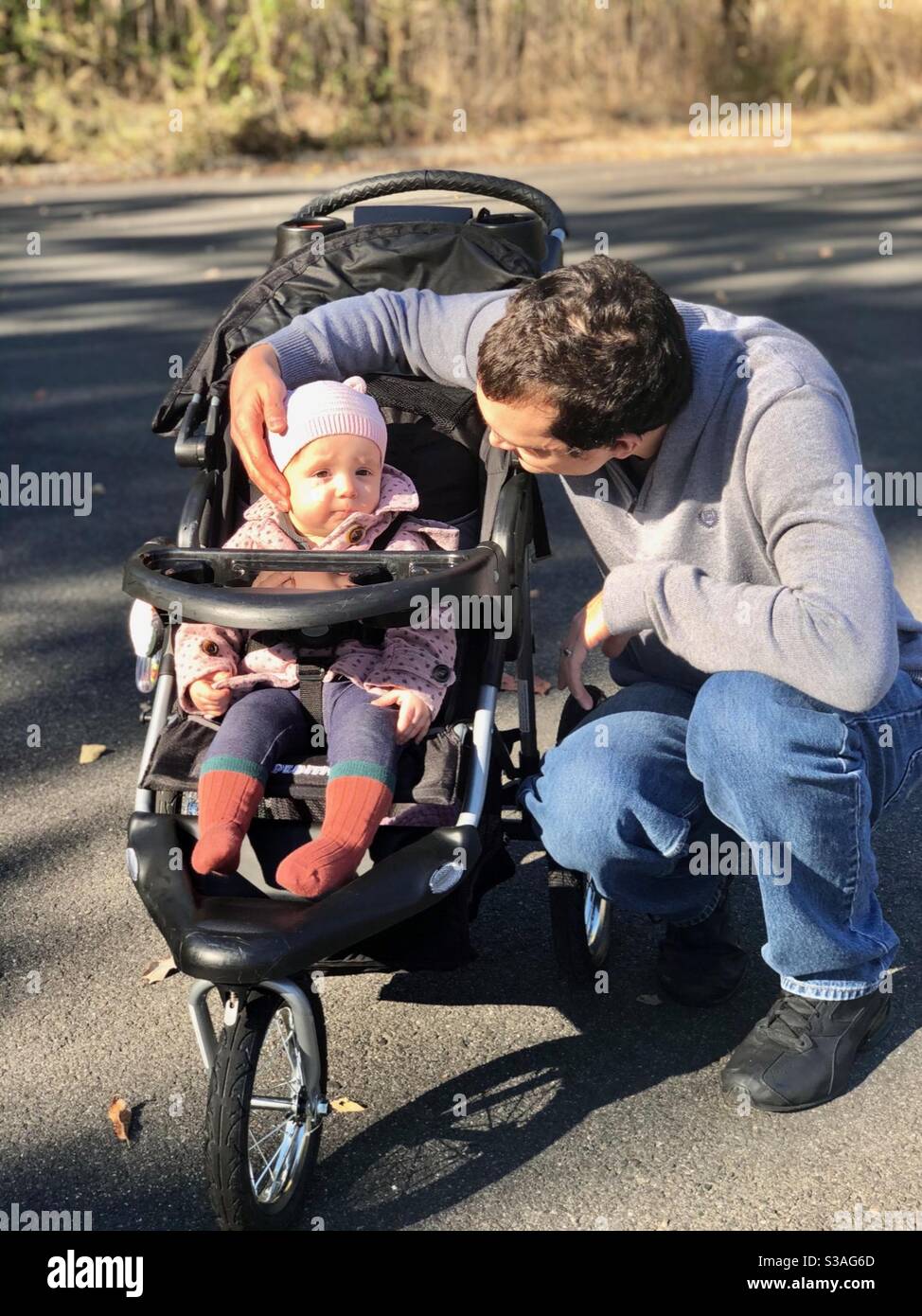Dad caressing baby daughter’s face in a stroller. Stock Photo