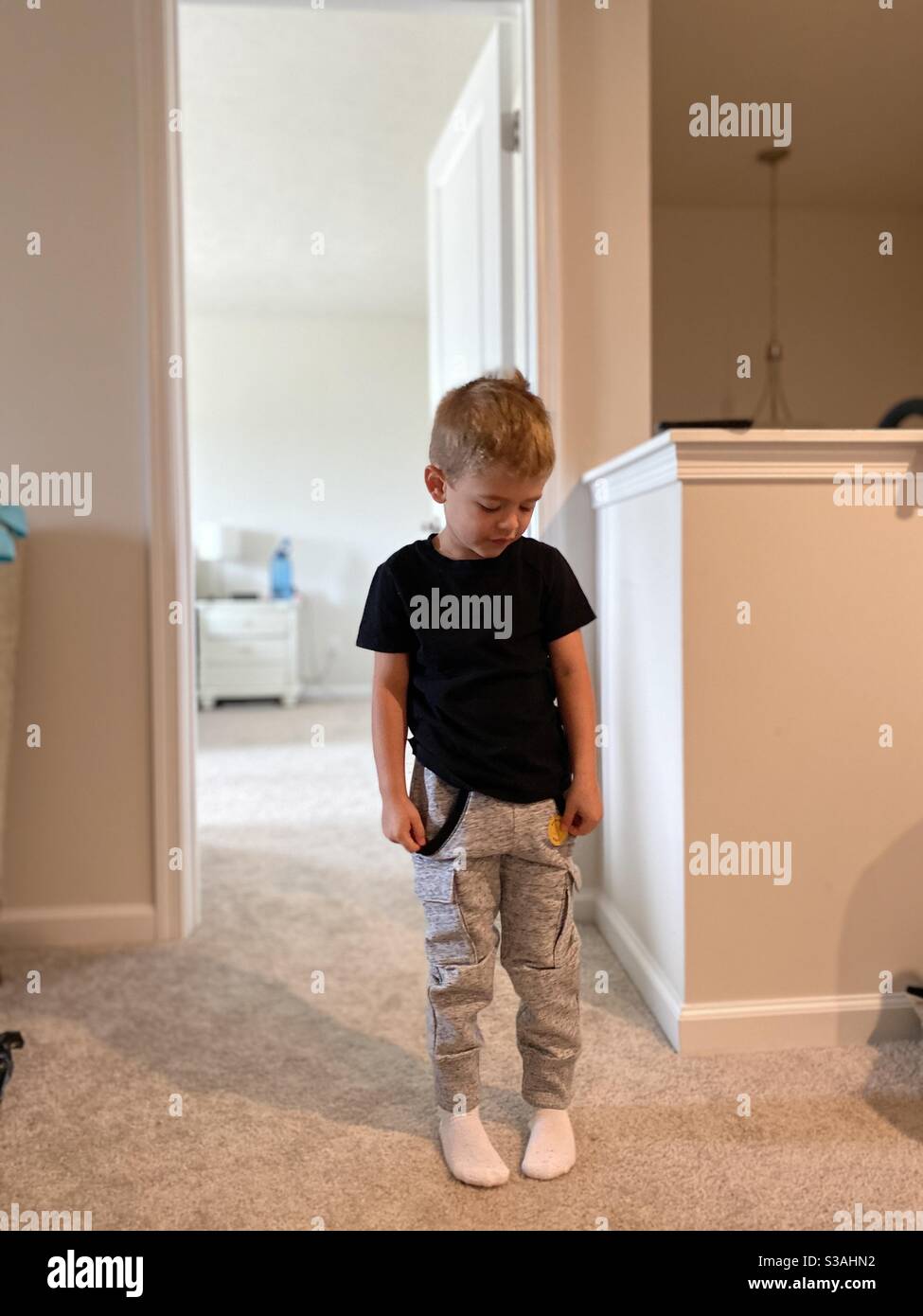 Blonde boy dressed up in grey sweats and black shirt, all ready for the busy day planned ahead Stock Photo